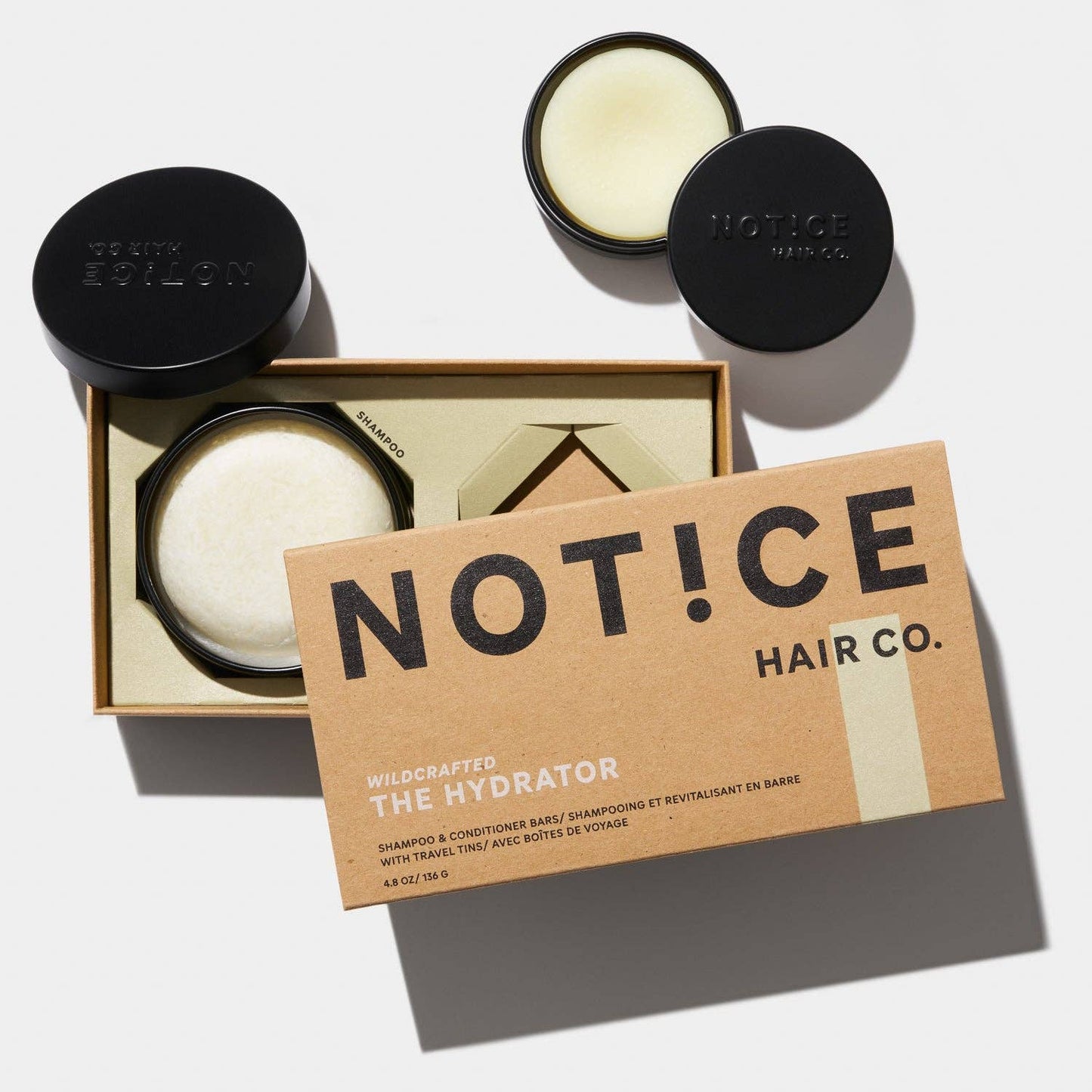 Solid round bars of shampoo and conditioner in black metal travel cases. Refillable eco friendly zero waste hair care.
