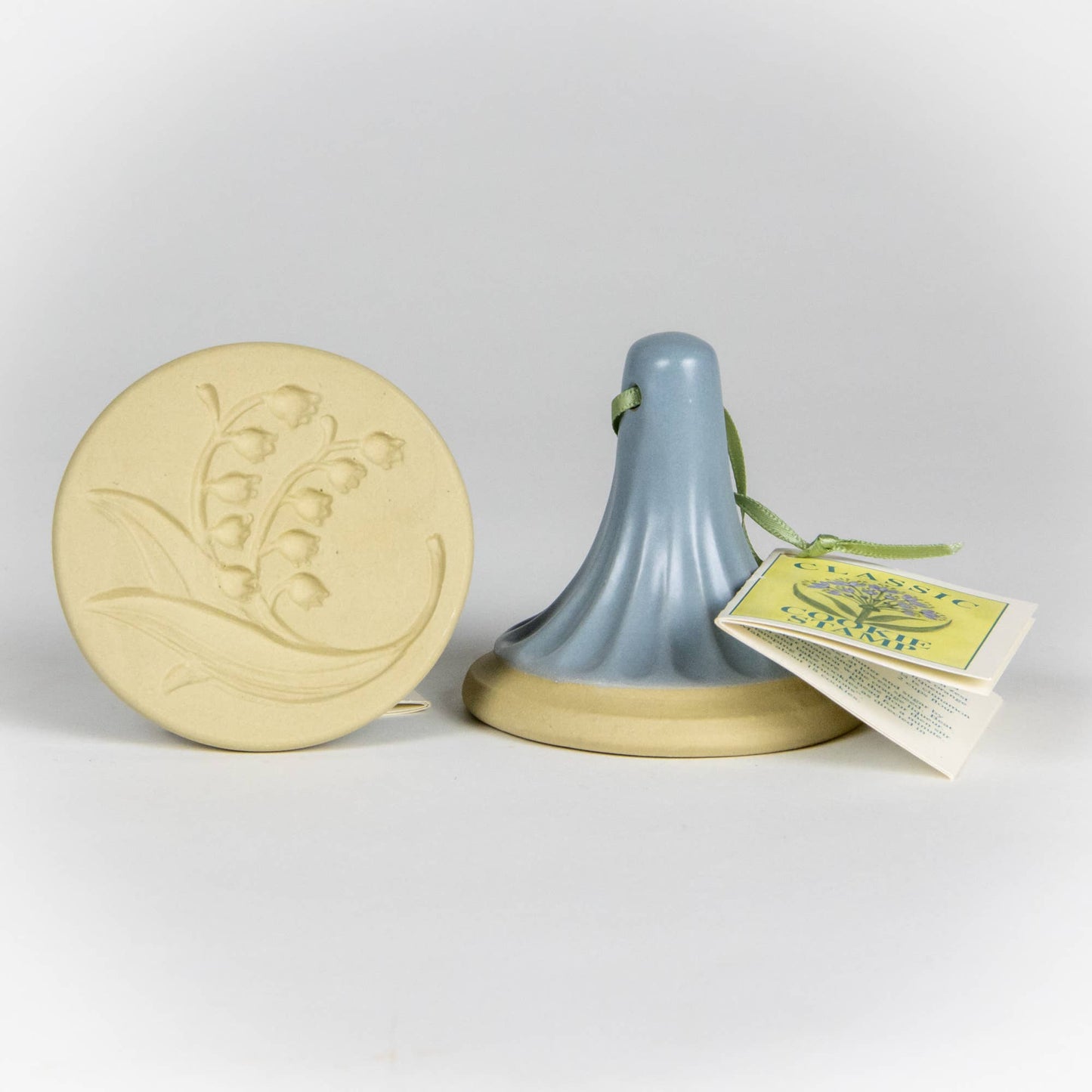 Stoneware ceramic cookie stamp by Emerson Creek. Lilly of the Valley design. Comes with small booklet with cookie recipes attached. Blue handle.