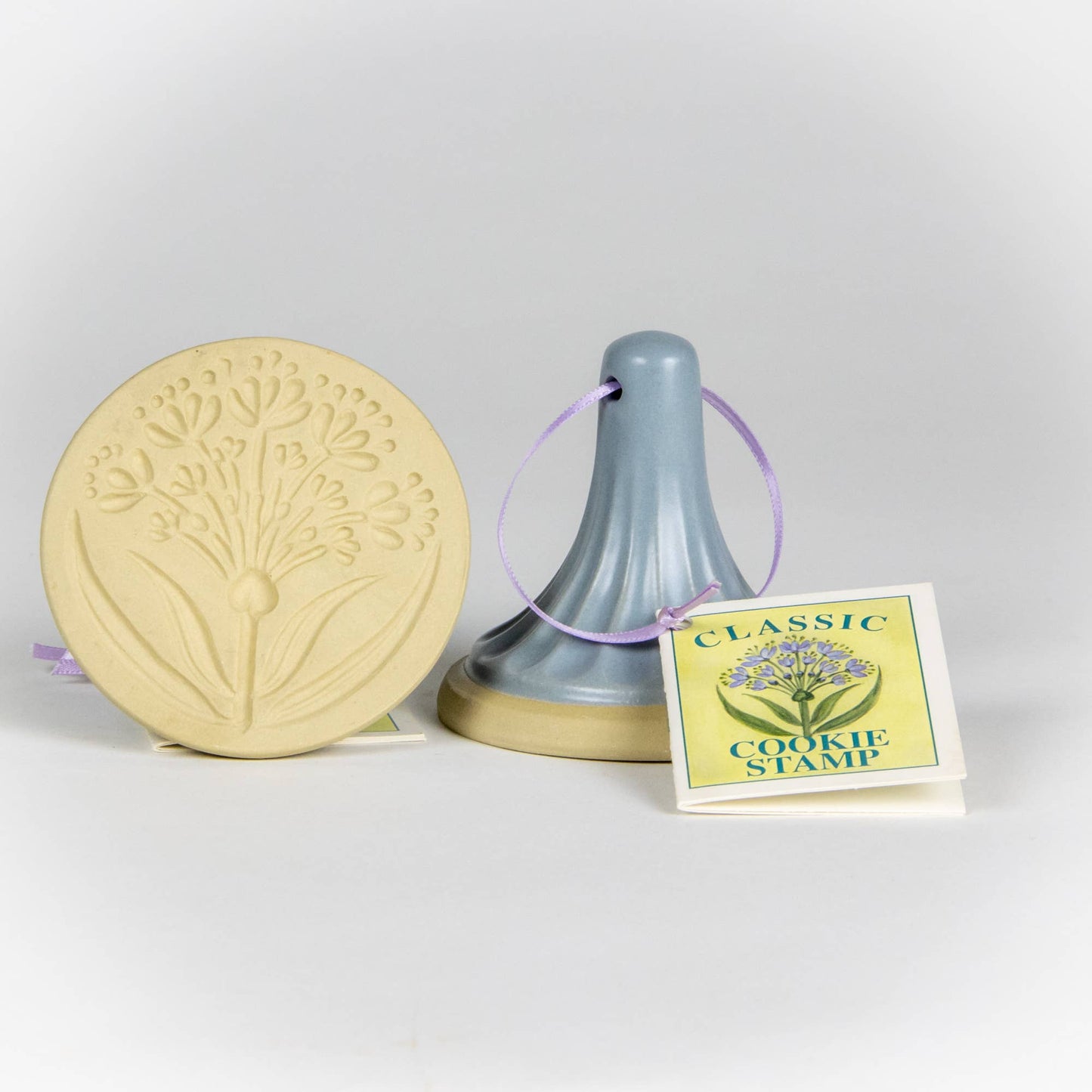Stoneware ceramic cookie stamp by Emerson Creek. Allium design. Comes with small booklet with cookie recipes attached. Blue handle.
