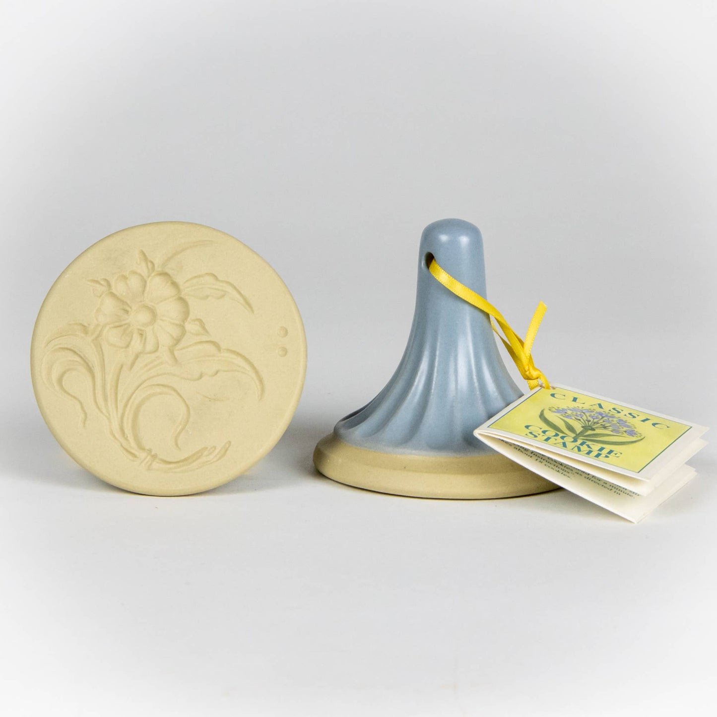 Stoneware ceramic cookie stamp by Emerson Creek. Woodland flower design. Comes with small booklet with cookie recipes attached. Blue handle. 