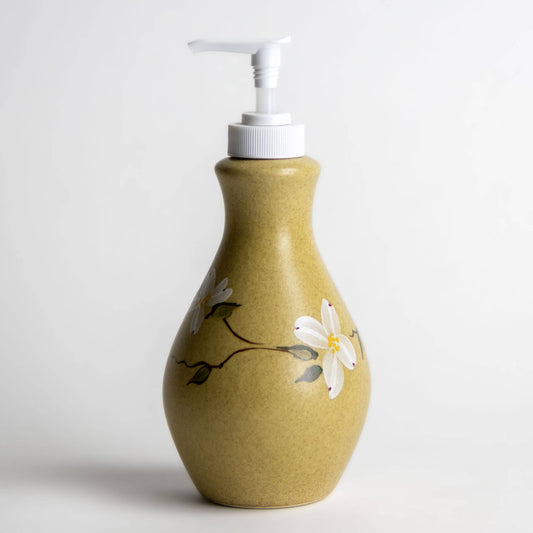 Stoneware refillable soap or lotion bottle with a white pump top. Hand painted dogwood flowers on the sides. Speckled olive green color. Zero waste home. 