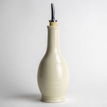 Creamy white stoneware olive oil or vinegar drizzle bottle with a cork and metal drizzle top.