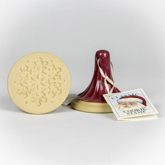 Stoneware ceramic cookie stamp by Emerson Creek. Snowflake design. Comes with small booklet with cookie recipes attached. Burgundy red handle. 