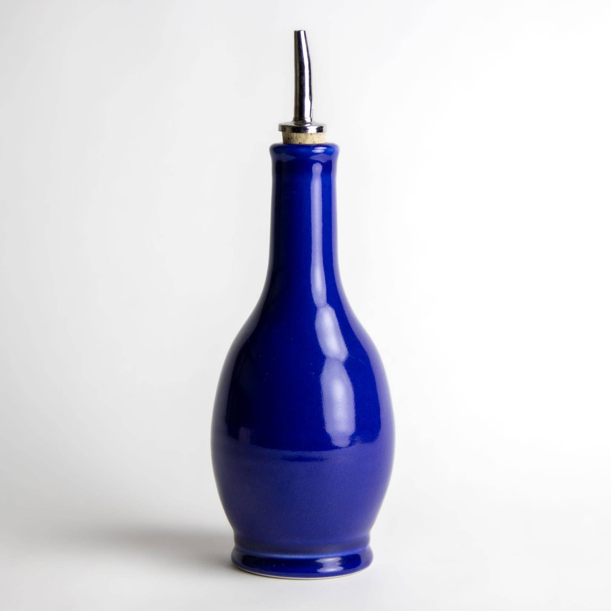 Vibrant blue stoneware olive oil or vinegar drizzle bottle with a cork and metal drizzle top. 