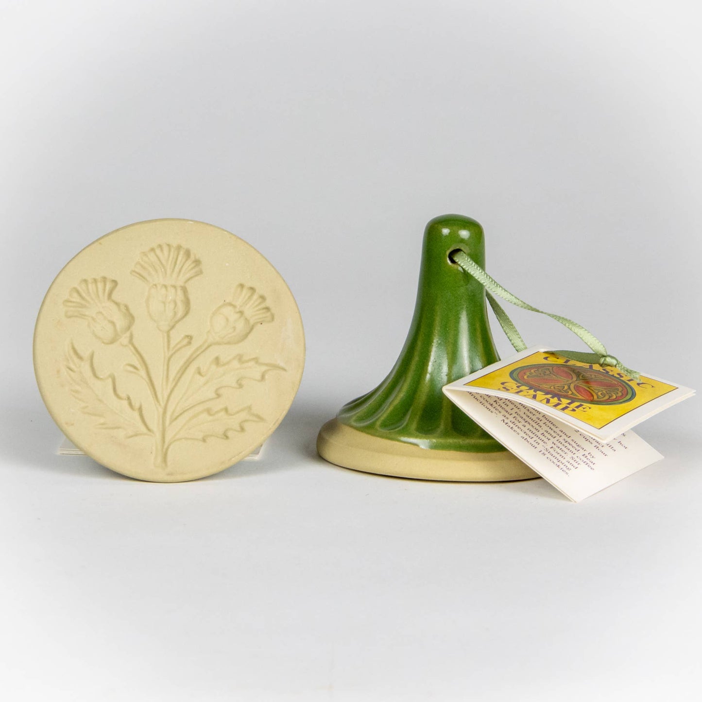 Stoneware ceramic cookie stamp by Emerson Creek. Thistle design. Comes with small booklet with cookie recipes attached. Green handle. 